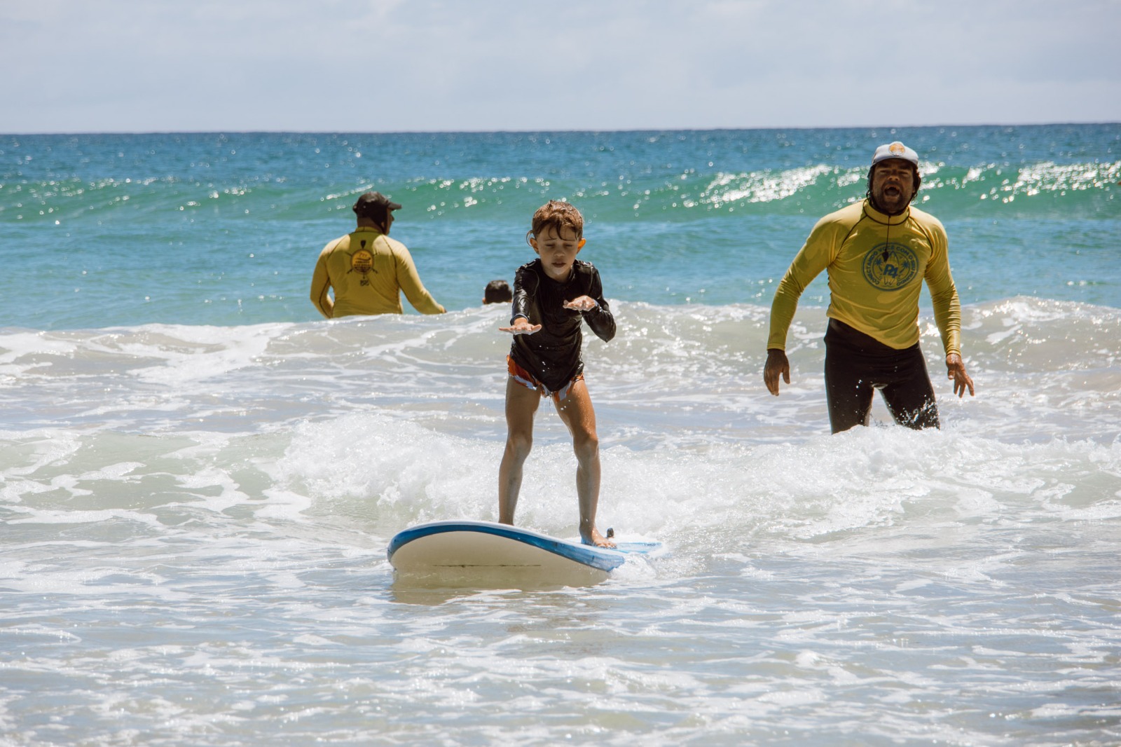 Criança surfando com instrutores em Canto Grande